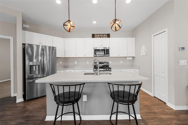 kitchen featuring sink, hanging light fixtures, appliances with stainless steel finishes, and a center island with sink