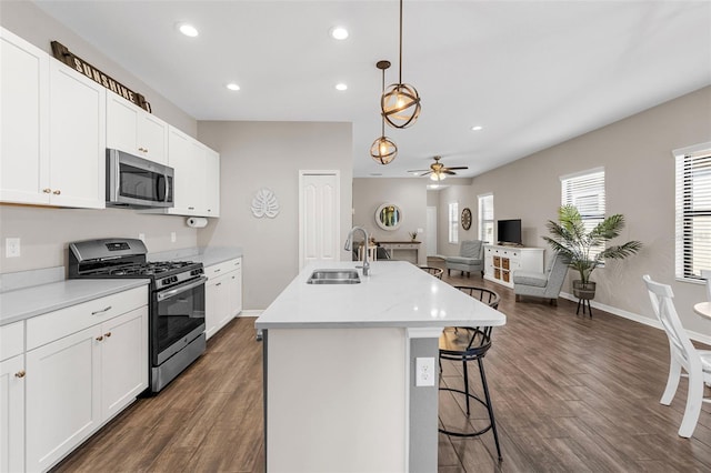 kitchen featuring sink, decorative light fixtures, white cabinets, an island with sink, and stainless steel appliances