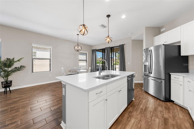 kitchen with white cabinetry, sink, pendant lighting, stainless steel appliances, and a center island with sink