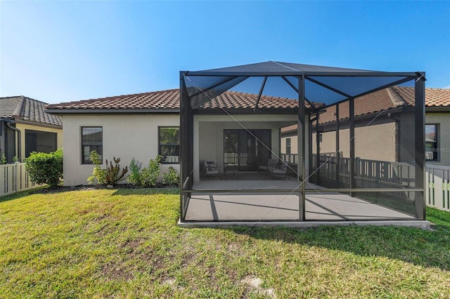 back of house with glass enclosure, a lawn, and a patio area