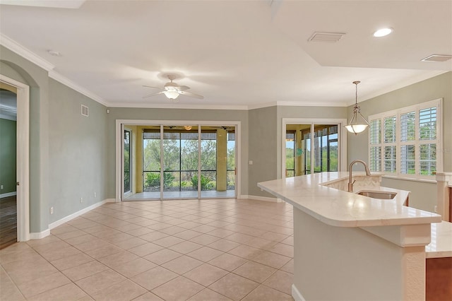 kitchen featuring sink, light tile patterned floors, ornamental molding, an island with sink, and pendant lighting