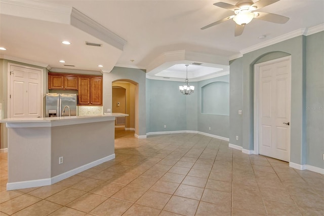 kitchen with decorative backsplash, crown molding, stainless steel fridge, and an island with sink