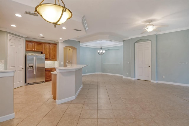 kitchen featuring ornamental molding, stainless steel fridge, decorative light fixtures, and a center island with sink