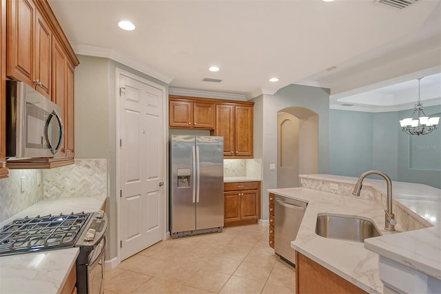 kitchen featuring sink, light stone counters, decorative light fixtures, ornamental molding, and appliances with stainless steel finishes