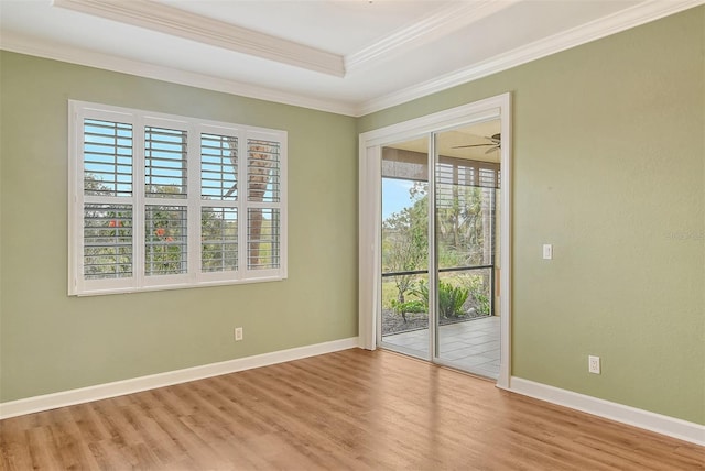 unfurnished room featuring ornamental molding, ceiling fan, light wood-type flooring, and a tray ceiling