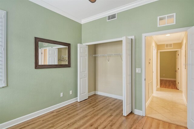 unfurnished bedroom featuring ornamental molding, light hardwood / wood-style floors, and a closet