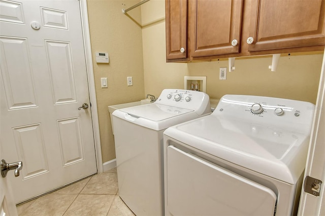 washroom featuring light tile patterned floors, washing machine and dryer, and cabinets