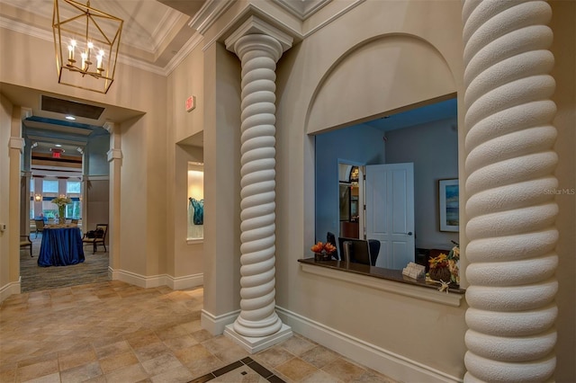 hall with crown molding, a towering ceiling, a chandelier, and decorative columns