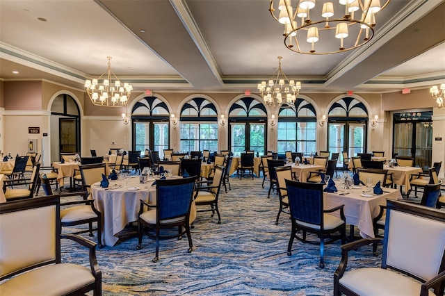 carpeted dining space with an inviting chandelier, a tray ceiling, french doors, and a wealth of natural light