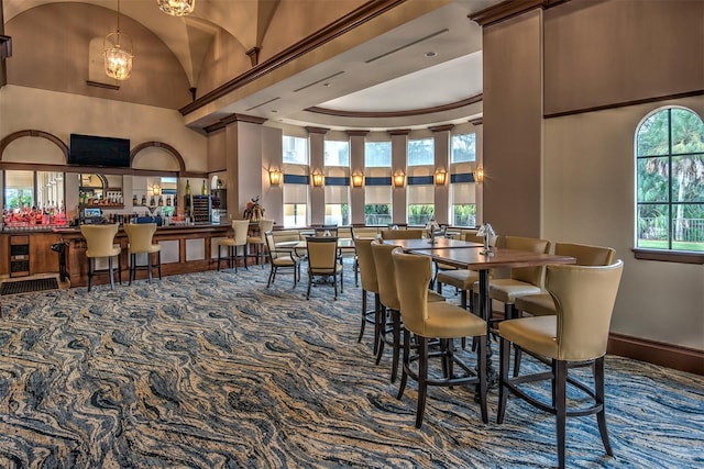 carpeted dining space with high vaulted ceiling and a chandelier