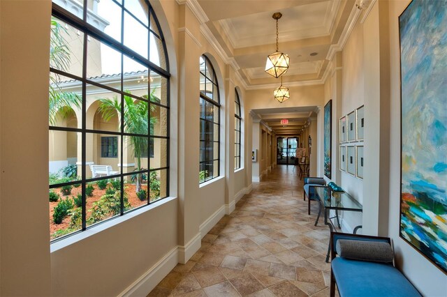 hallway featuring a tray ceiling, ornamental molding, and a high ceiling