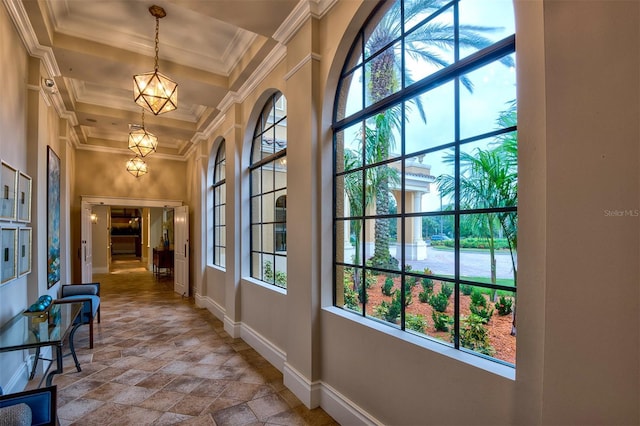 corridor with a high ceiling, crown molding, and plenty of natural light