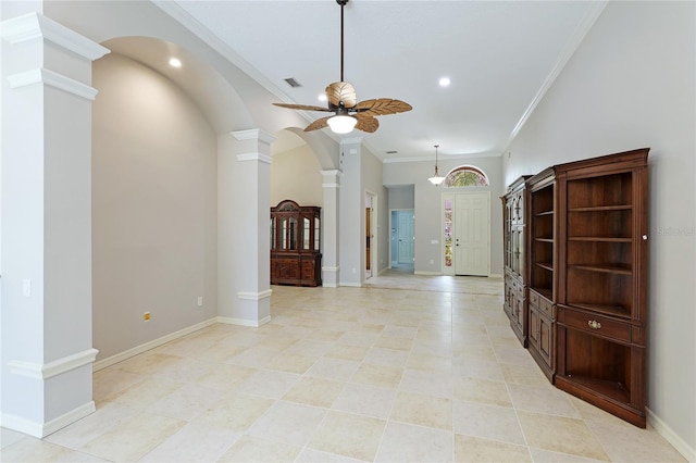 unfurnished living room featuring a towering ceiling, ornamental molding, ceiling fan, and ornate columns