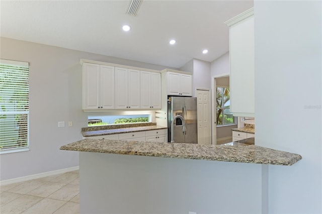 kitchen with white cabinetry, kitchen peninsula, light stone counters, and stainless steel fridge with ice dispenser