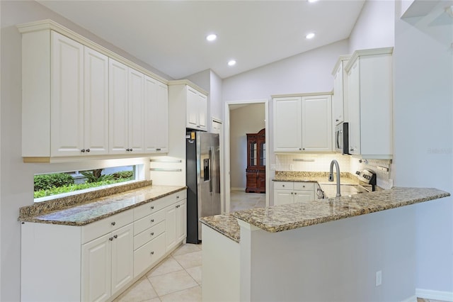 kitchen with vaulted ceiling, white cabinets, and appliances with stainless steel finishes