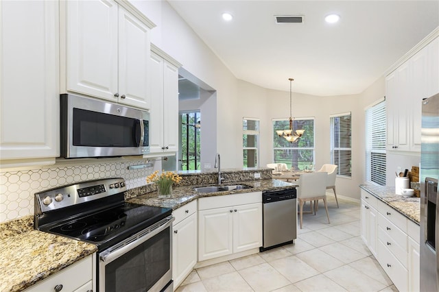 kitchen featuring lofted ceiling, sink, dark stone counters, stainless steel appliances, and white cabinets