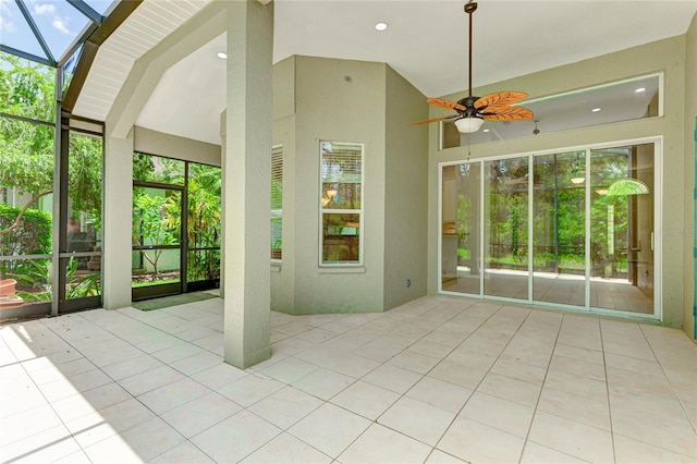 unfurnished sunroom with ceiling fan, a skylight, and a wealth of natural light