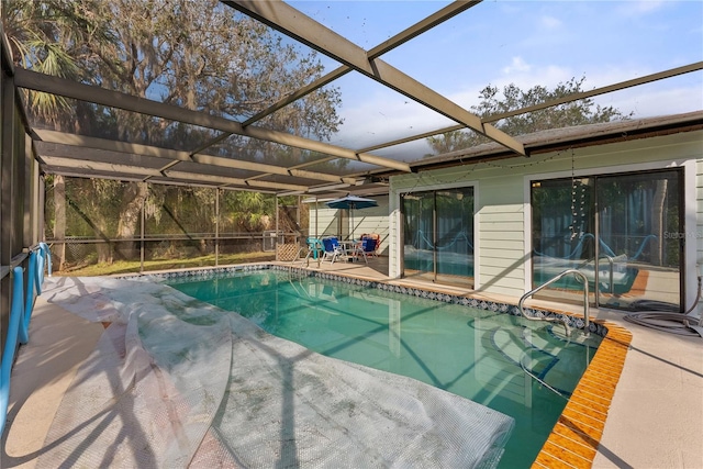 view of swimming pool featuring glass enclosure and a patio