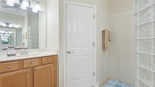 bathroom featuring vanity, tiled shower, crown molding, and ceiling fan