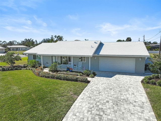 ranch-style home with a garage, a front lawn, and covered porch