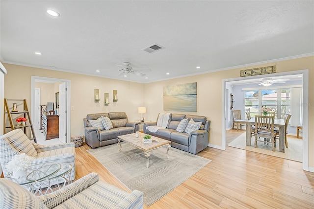 living room with ornamental molding, ceiling fan, and light wood-type flooring