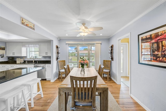 dining room with crown molding, sink, ceiling fan, and light wood-type flooring