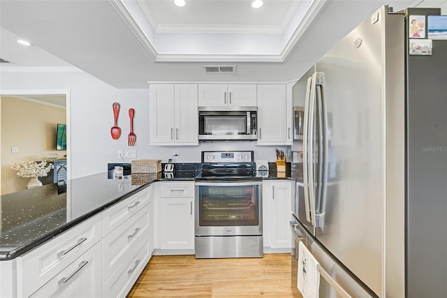 kitchen featuring appliances with stainless steel finishes, light hardwood / wood-style floors, kitchen peninsula, white cabinets, and dark stone counters