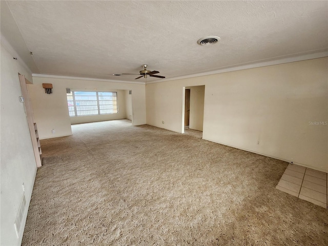 carpeted spare room with a textured ceiling, ornamental molding, and ceiling fan