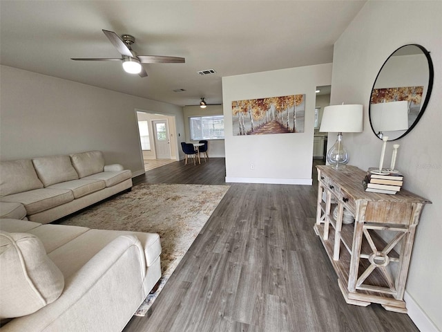 living room featuring dark wood-type flooring and ceiling fan