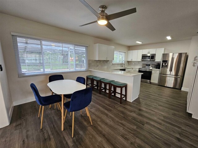 dining space featuring sink, dark wood-type flooring, and ceiling fan