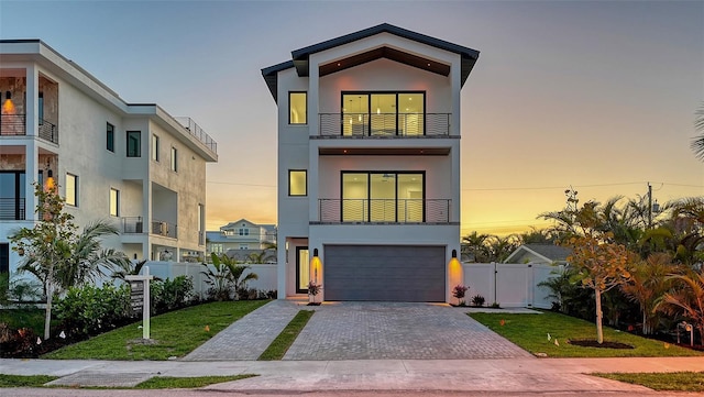 contemporary house with a garage, a balcony, and a lawn