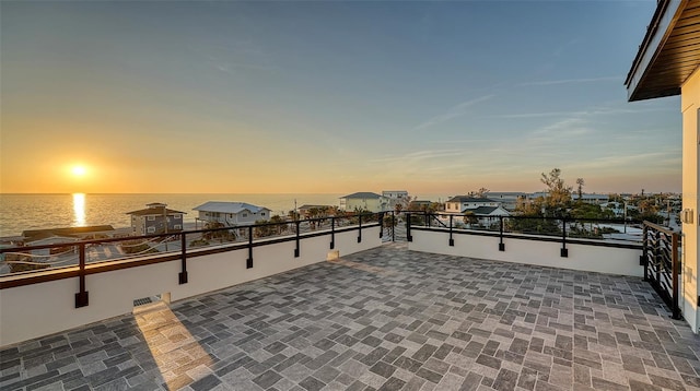 patio terrace at dusk with a water view and a balcony