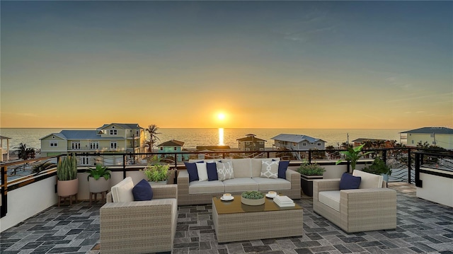 patio terrace at dusk with a water view and an outdoor living space