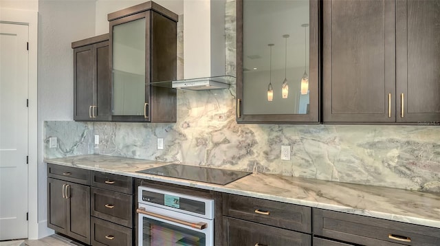 kitchen featuring black electric cooktop, light stone counters, oven, and wall chimney exhaust hood