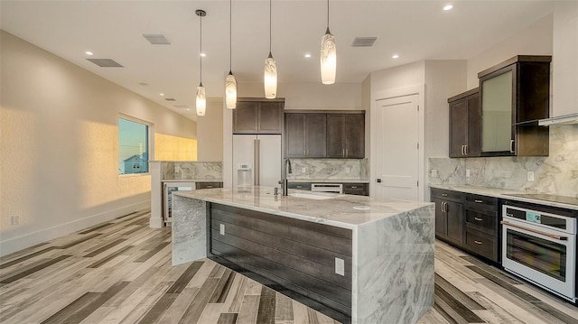 kitchen with light stone counters, white appliances, a sink, visible vents, and a large island