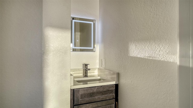 bathroom with a textured wall and vanity