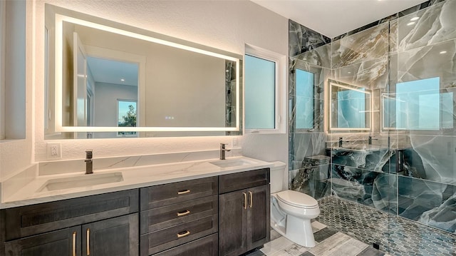 full bathroom with double vanity, a stall shower, a sink, and toilet