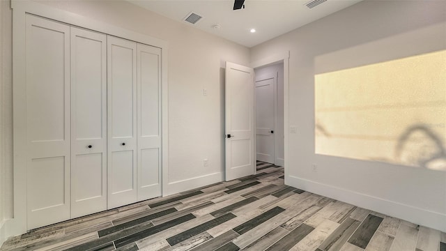 unfurnished bedroom with a closet, light wood-type flooring, visible vents, and baseboards