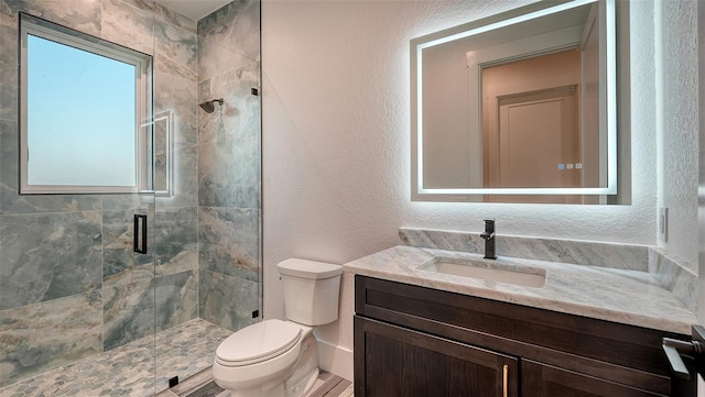 full bathroom with toilet, a stall shower, vanity, and a textured wall