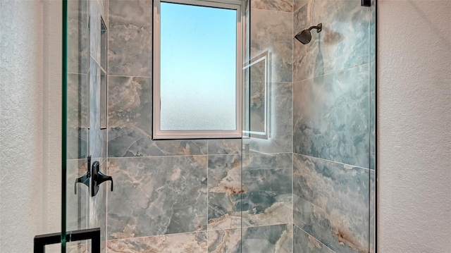 full bathroom featuring a textured wall and tiled shower