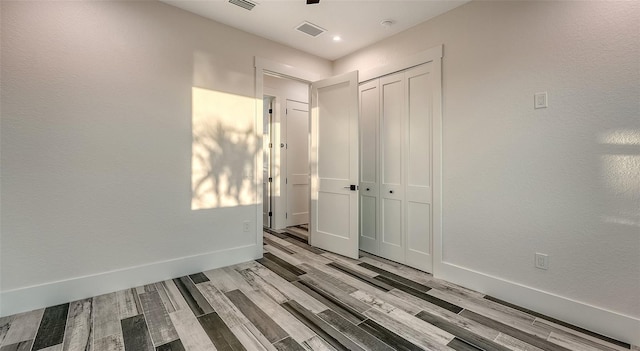 spare room featuring visible vents, baseboards, and wood finished floors