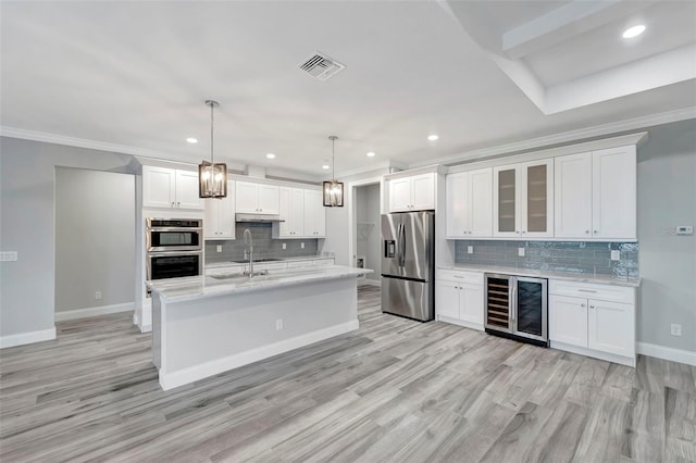 kitchen with hanging light fixtures, stainless steel appliances, beverage cooler, and white cabinets