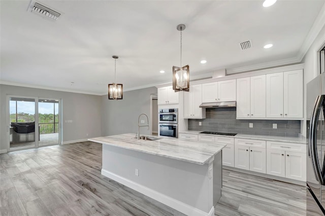 kitchen with appliances with stainless steel finishes, decorative light fixtures, white cabinetry, sink, and a center island with sink