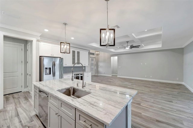 kitchen with pendant lighting, sink, white cabinets, a kitchen island with sink, and stainless steel appliances