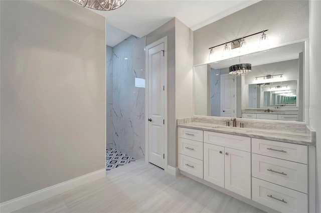 bathroom with vanity, tiled shower, and an inviting chandelier