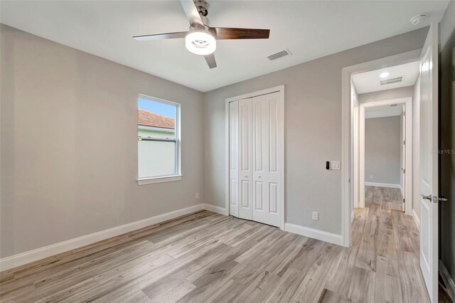 unfurnished bedroom with light hardwood / wood-style flooring, a closet, and ceiling fan