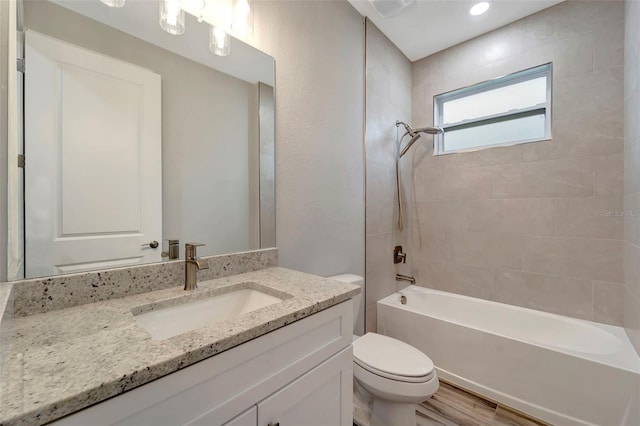 full bathroom featuring tiled shower / bath combo, vanity, hardwood / wood-style flooring, and toilet