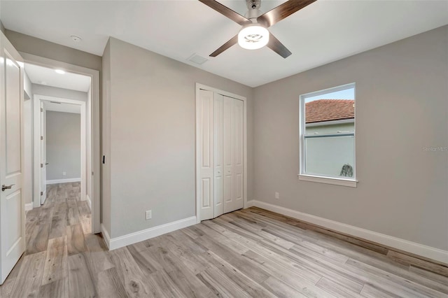 unfurnished bedroom with ceiling fan, light wood-type flooring, and a closet