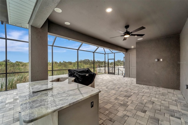 view of patio / terrace with area for grilling, ceiling fan, and glass enclosure