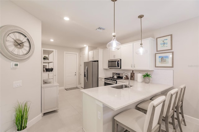 kitchen featuring pendant lighting, sink, stainless steel appliances, white cabinets, and kitchen peninsula